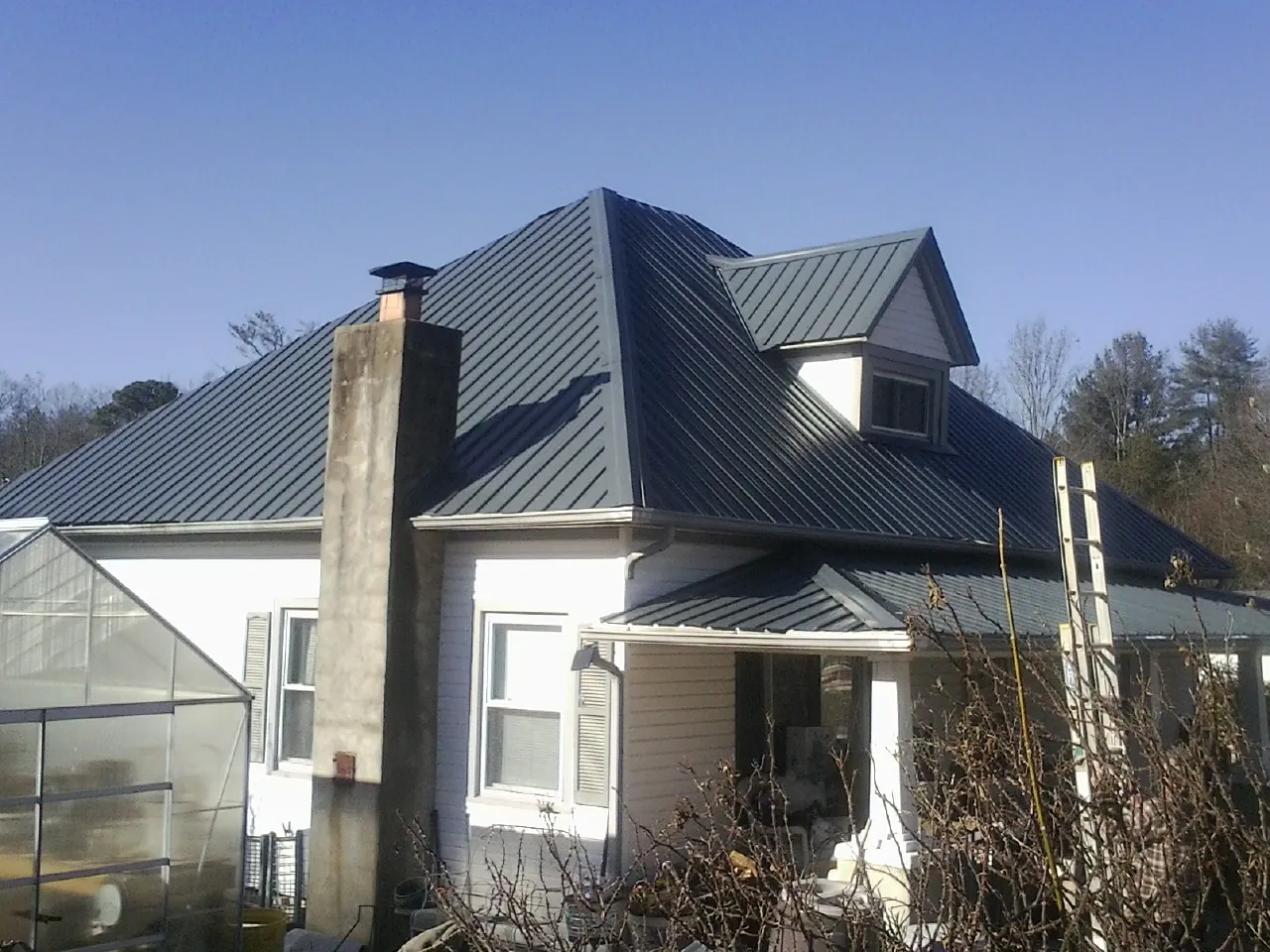 Dark blue standing seam metal roof on a white farmhouse with dormer — Slate & Tile Roof Repair by Roofing Brothers in Bingham Canyon