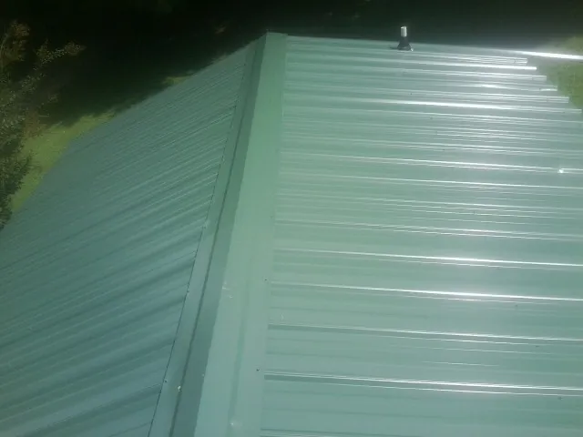 New green metal panels meeting at the ridge of a roof — Flat Roof Repair work by our crew in Bingham Canyon