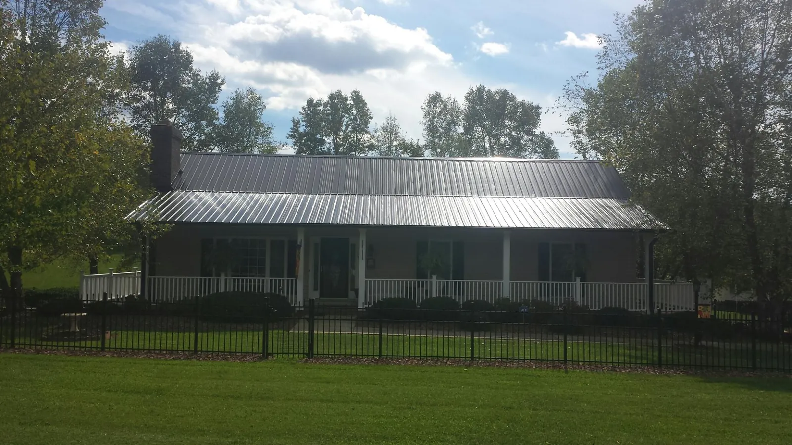 Gray metal roof on a brick ranch with a full width front porch — Gutter Guard Installation work by our crew in Bingham Canyon